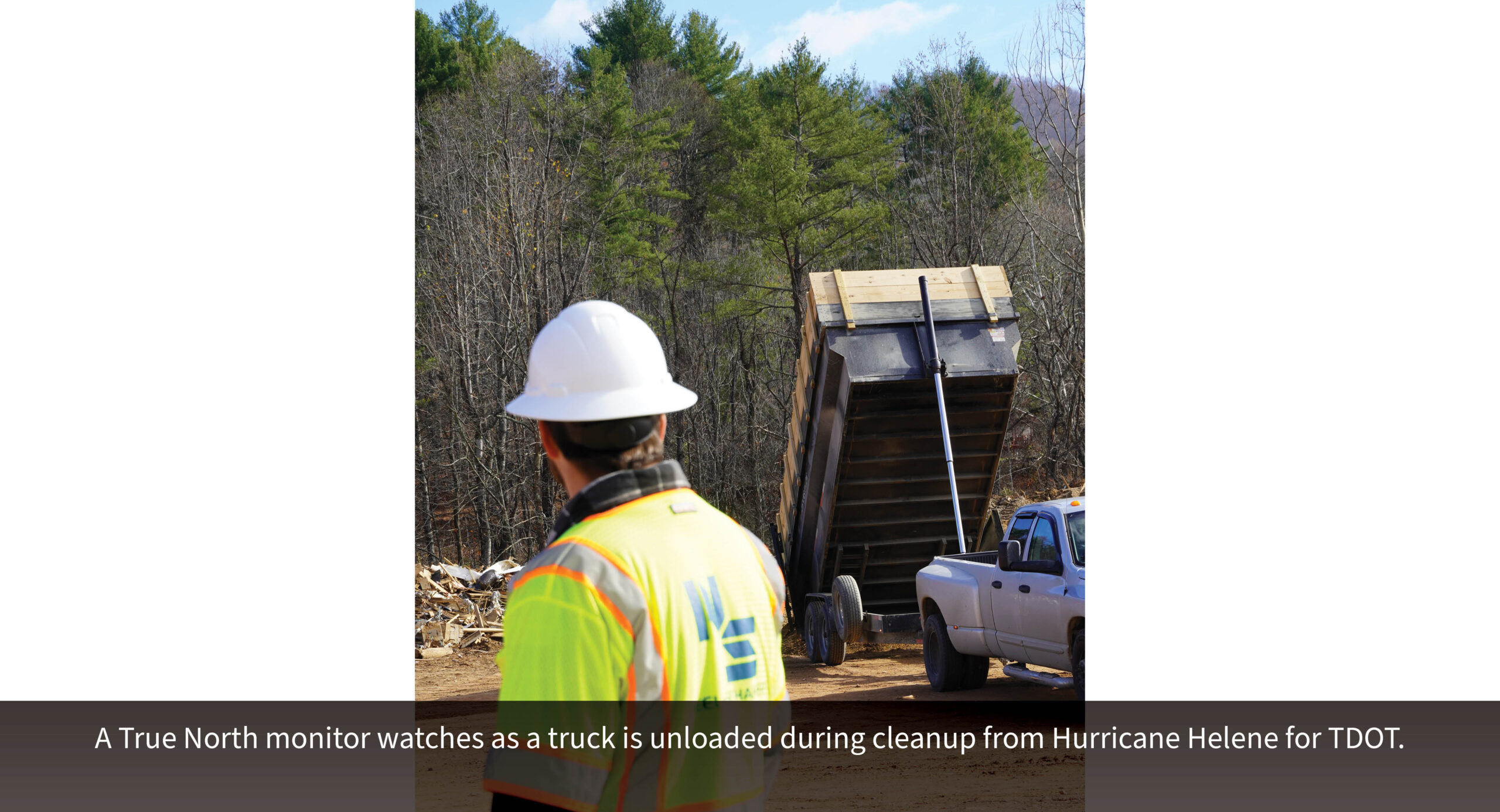 A True North monitor watches as a truck is unloaded during cleanup from Hurricane Helene for TDOT.
