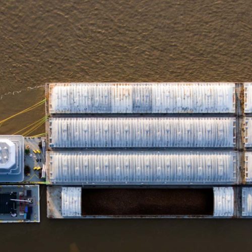 An overhead view of cargo containers on a concrete structure surrounded by water.