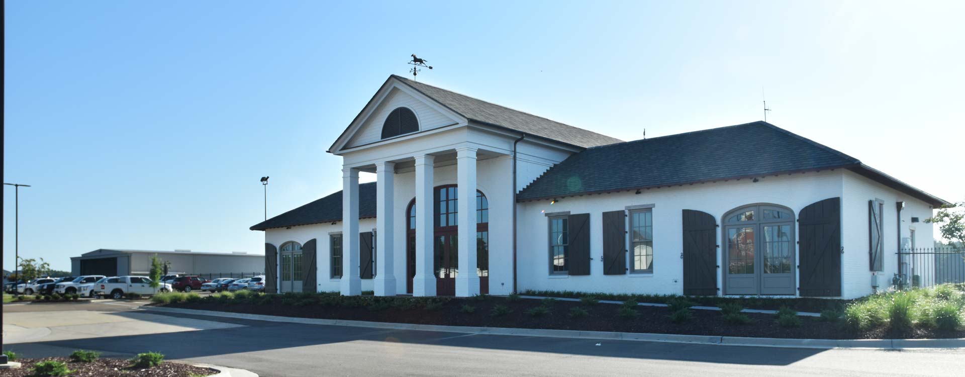 A front view of the building for the hangar and terminal. It's a white building with four columns in front and a grey roof.