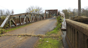 An old, rusty bridge where grass is growing through the cracks in the pavement.