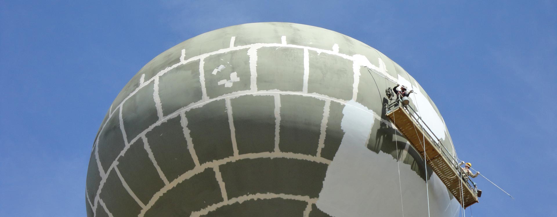 Two people painting the dome of a water tower.