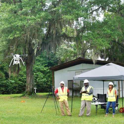 Construction workers operating a drone outdoors.