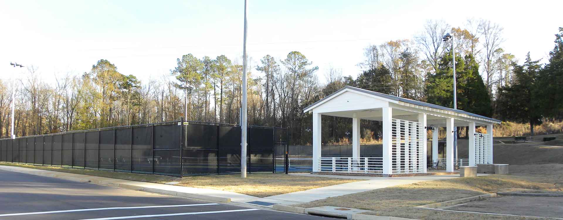 The Brandon Tennis facility, surrounded by fence, and with a white covered pavillion on the side.