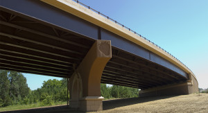 An image looking up at a bridge. One of the columns that supports the bridge has a strawberry design carved into the side.