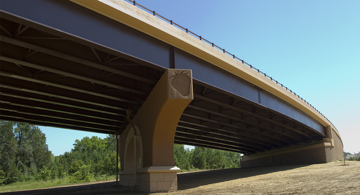 An image looking up at a bridge. One of the columns that supports the bridge has a strawberry design carved into the side.