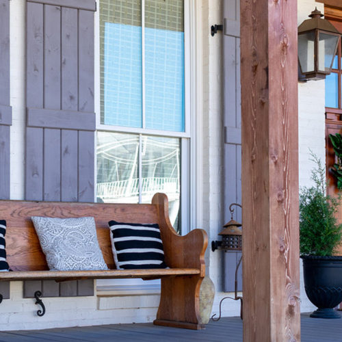 A front porch with a wooden bench covered in throw pillows.