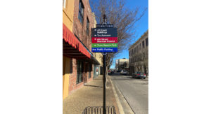 A sign on a sidewalk that points directions to "All Court Buildings," "6th Street Museum District," "Town Square Park," and "Public Parking."